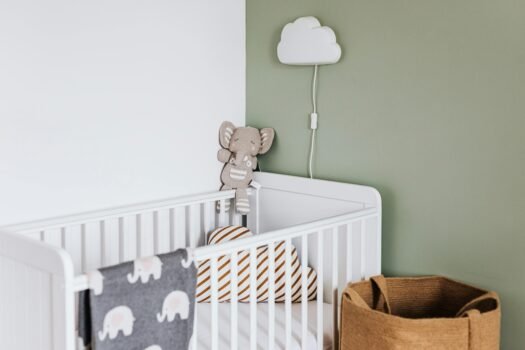 Modern baby room featuring a white crib, soft decor, and pastel accents.